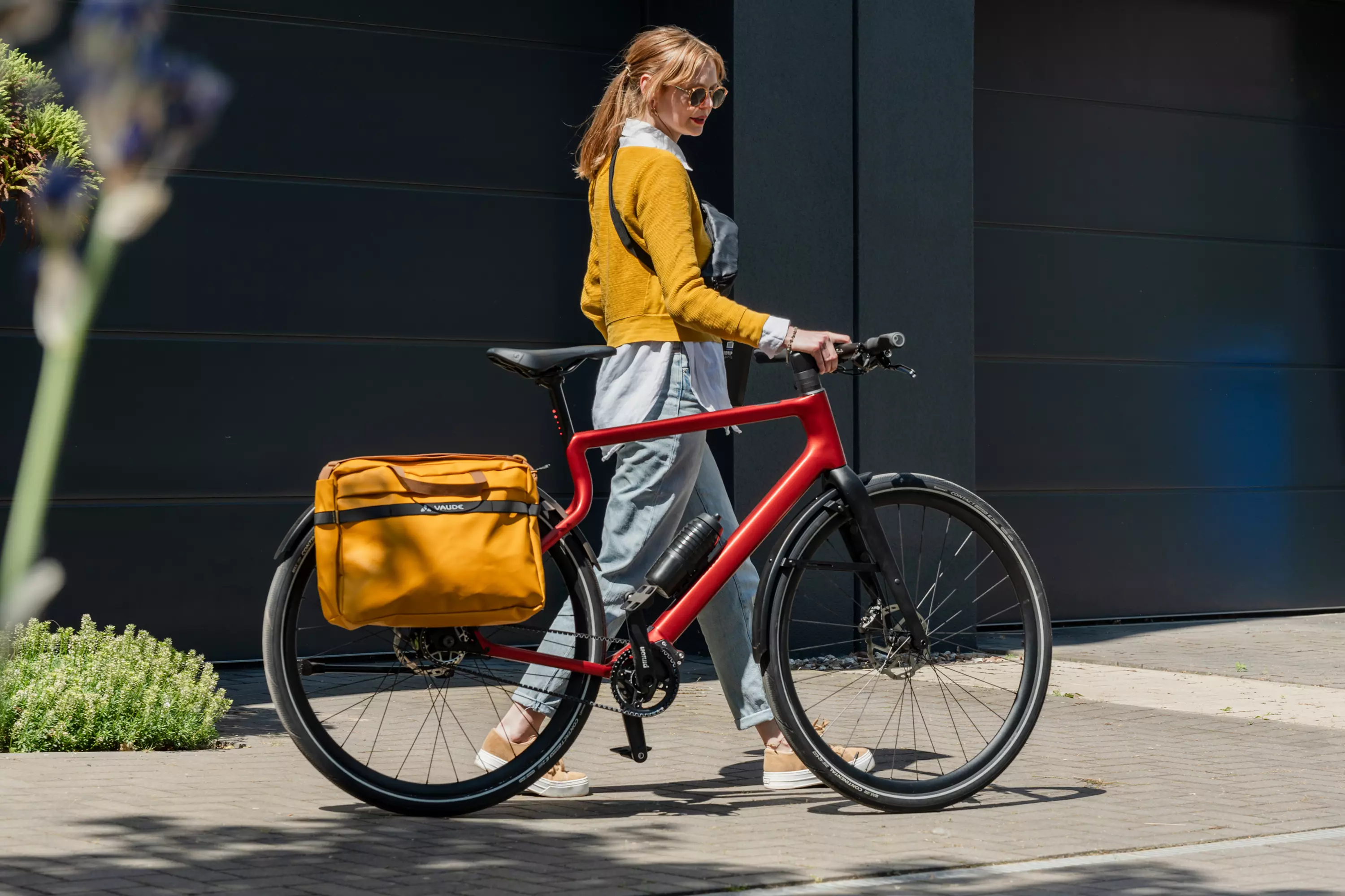 Junge modische Frau schiebt ihr oxidfarbenes Urban E-Bike Stadtfuchs