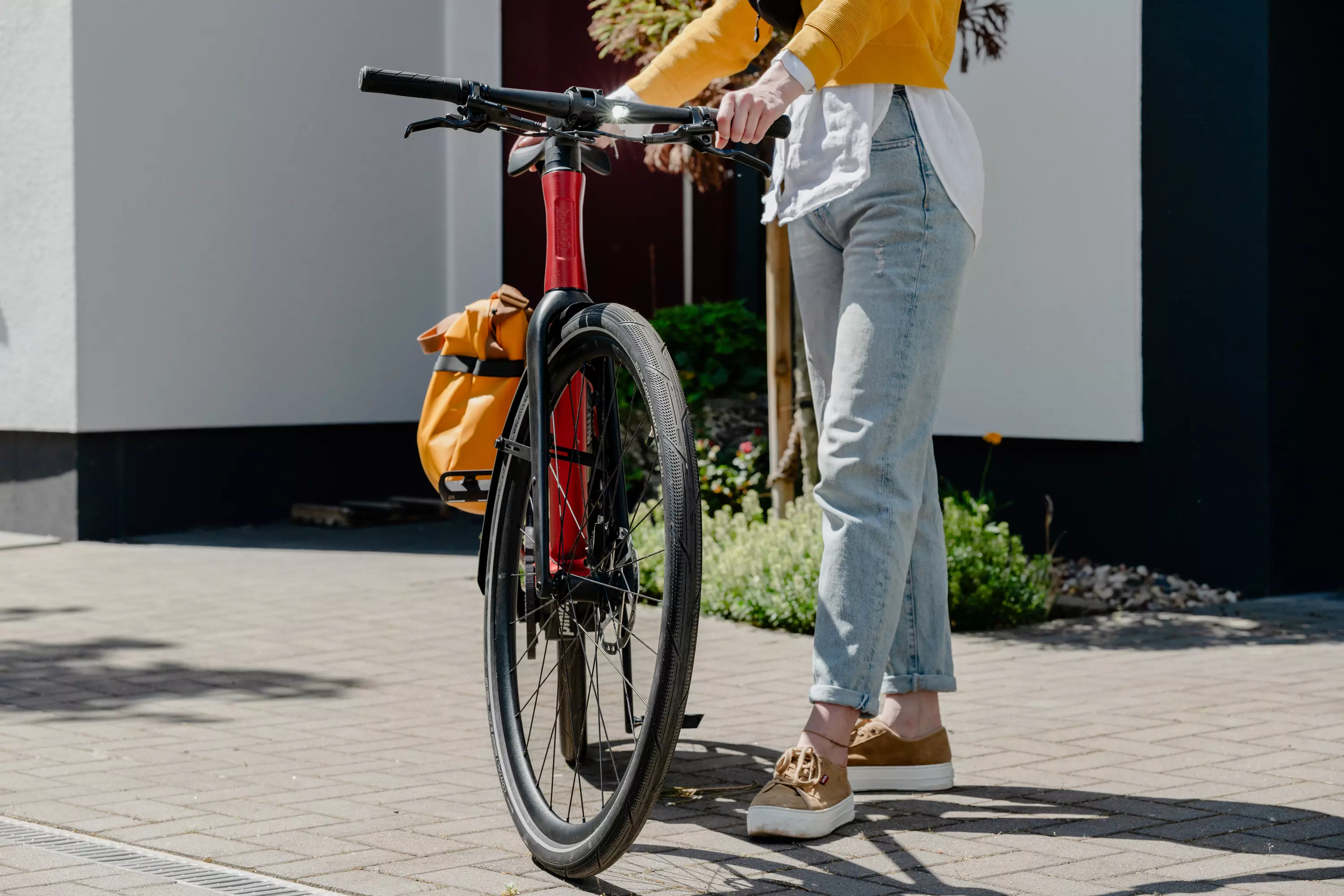 Detailaufnahme einer schlanken Frau, die leicht auf dem Oberrohr des oxidfarbenen E-Bikes Stadtfuchs sitzt