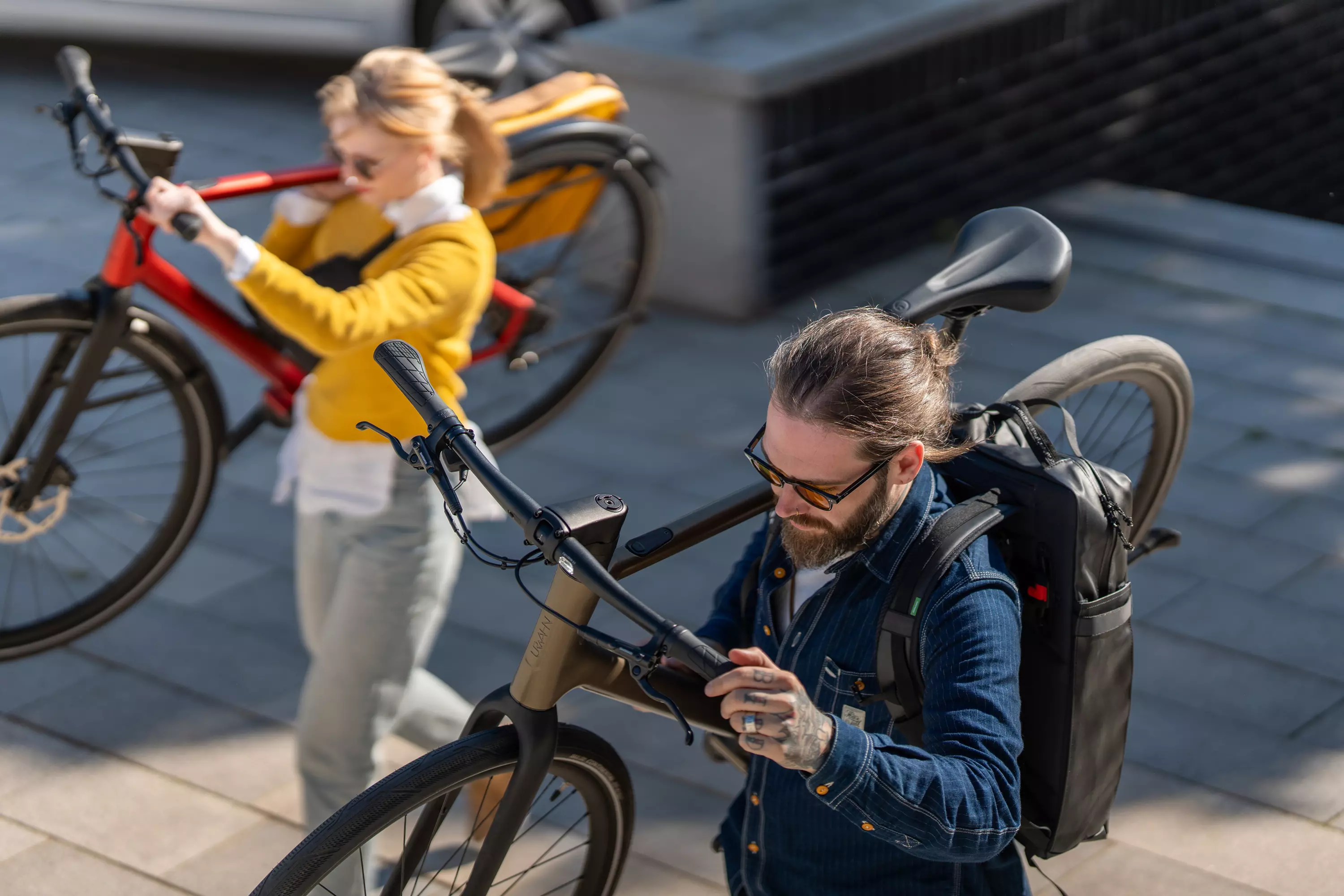 Junges Pärchen schultert ihre leichten Urwahn Stadtfuchs E-Bikes mit Leichtigkeit