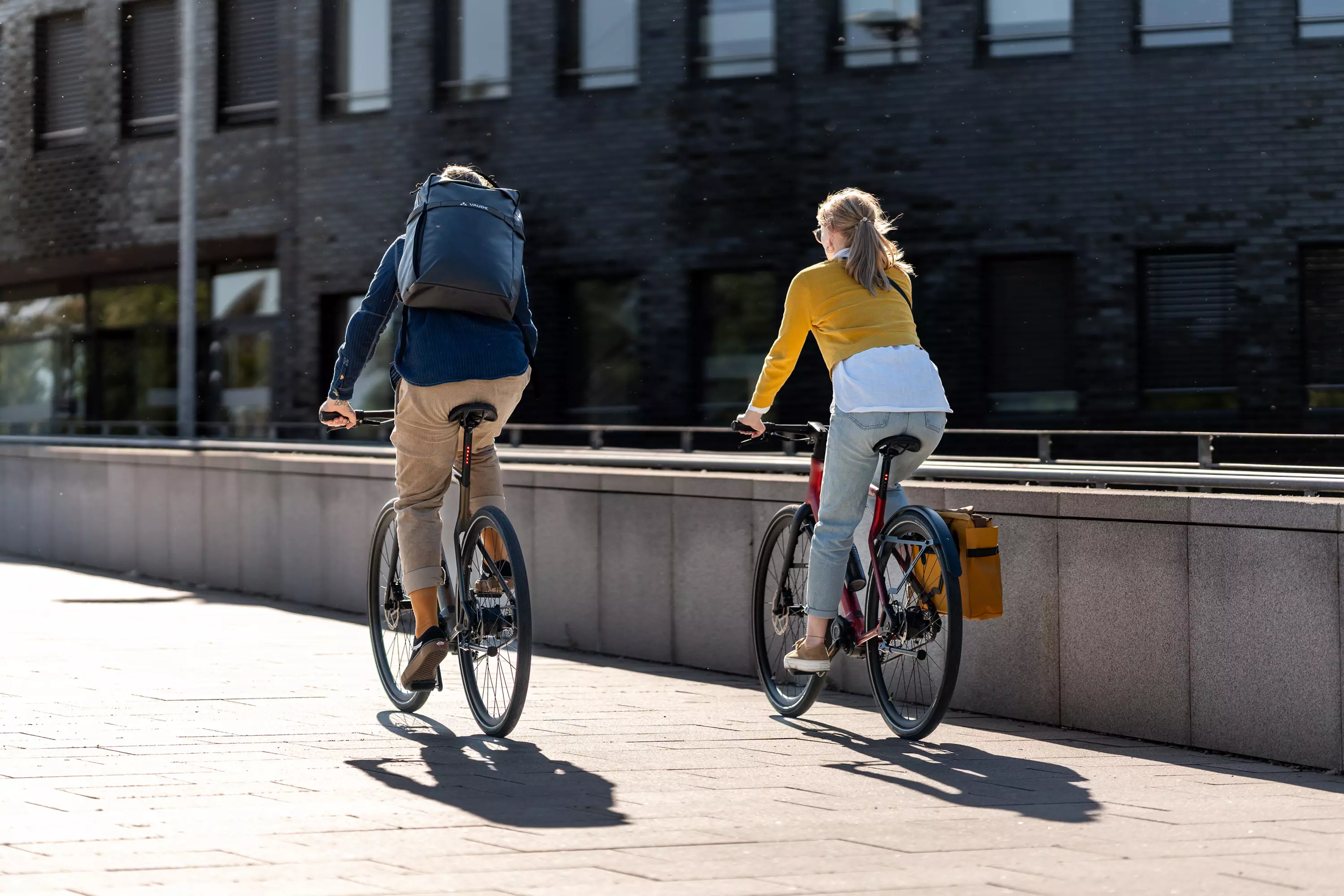 Junges Pärchen in Rückansicht, zusammen unterwegs auf ihren Stadtfuchs Urban E-Bikes