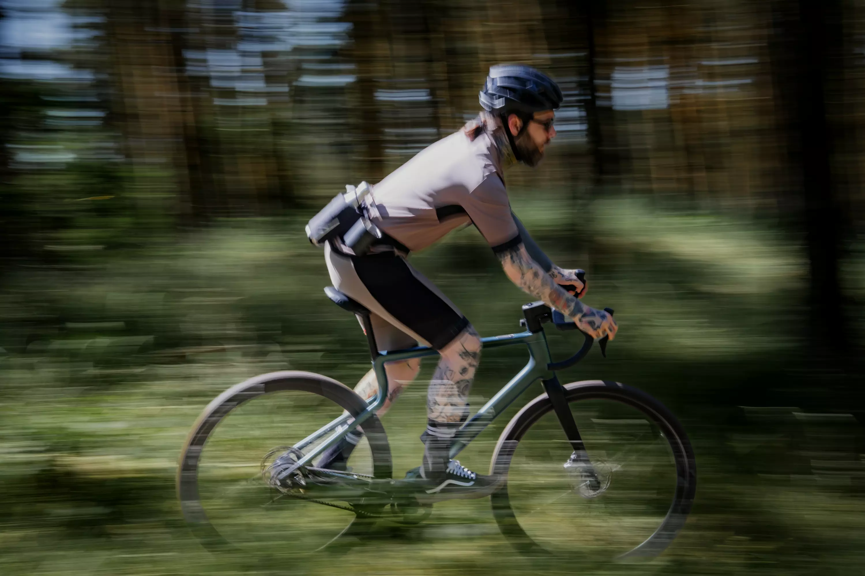 Ein sportlicher junger Mann saust mit seinem leichten Gravel E-Bike Waldwiesel durch den Wald