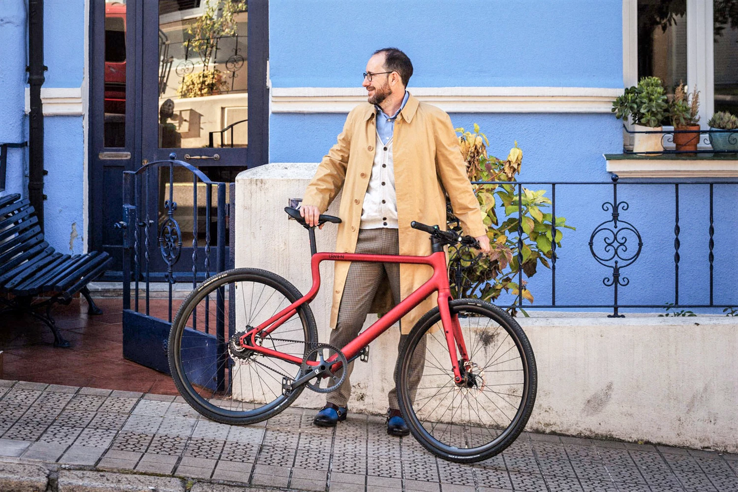 E-Bike Stadtfuchs in Oxidrot wird von einem elegant gekleideten Mann an der Seite einer Straße gehalten